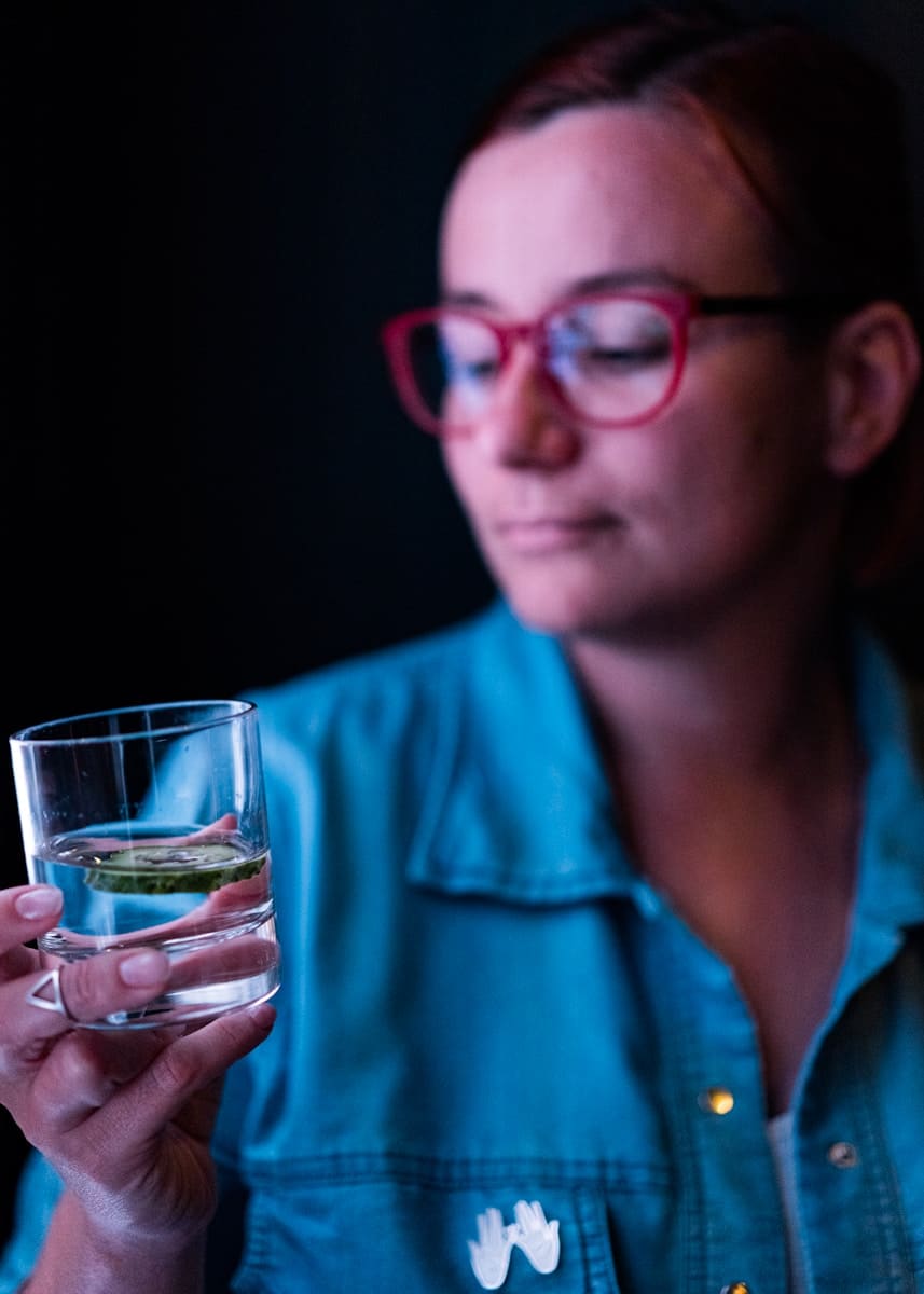 a woman wearing glasses holding a glass of water - Chemical-Free Sanctuary