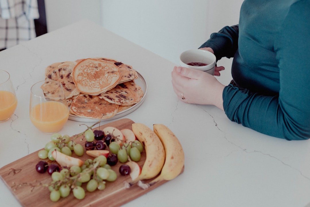 a woman sitting at a table with a plate of fruit and pancakes- Sleep and Longevity