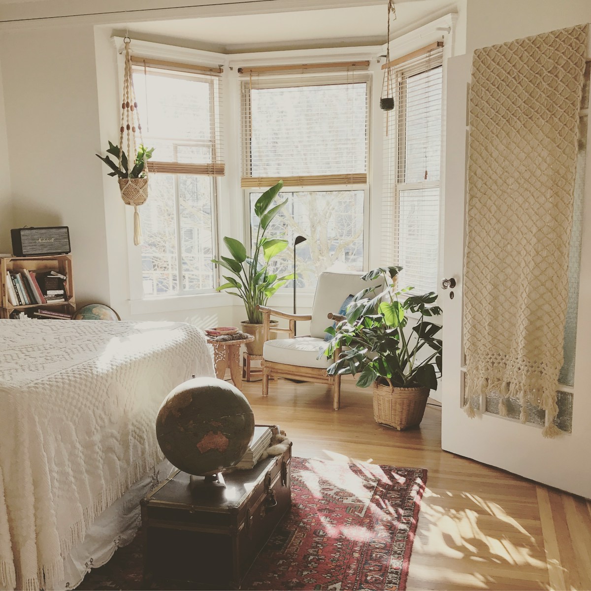 brown wooden framed white padded chair in between green indoor leaf plants inside bedroom - Air Quality