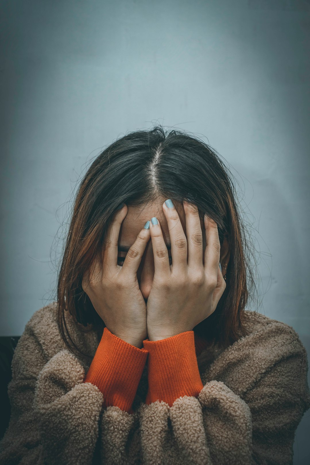 woman in brown sweater covering her face with her hand - The Gut-Brain Axis