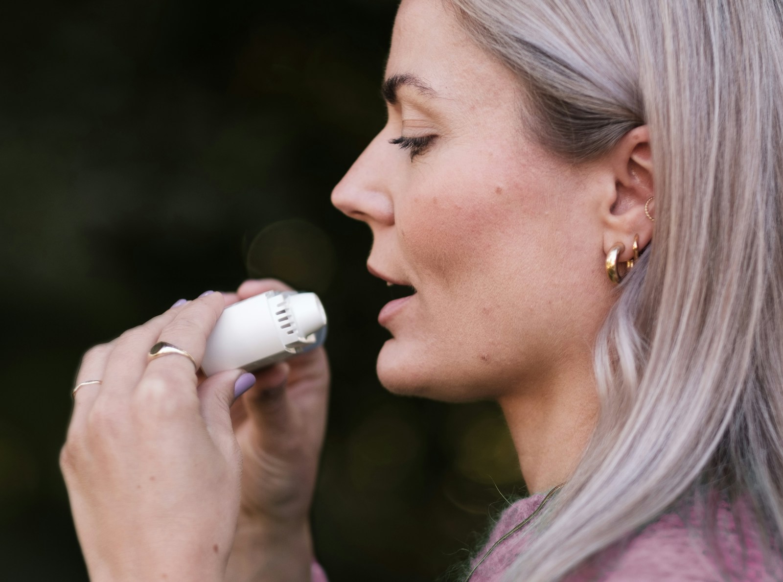 A woman with grey hair is using a hair dryer