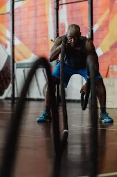 Man engaged in a dynamic battle rope exercise at a gym, showcasing strength