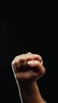 A powerful close-up of a fist raised against a dark background symbolizing
