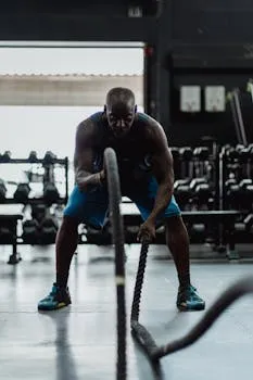 Athlete pausing to rest after intense battle ropes training showing balanced