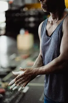 Man standing still in gym with chalk on hands embodying calm confident