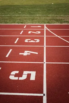 Close-up view of a red running track with numbered starting lanes, perfect
