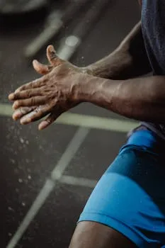 Close-up of an athlete clapping chalked hands before exercise in the gym.