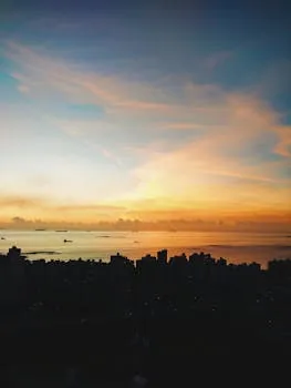 Breathtaking sunrise over city skyline with vibrant colors and calm sea,