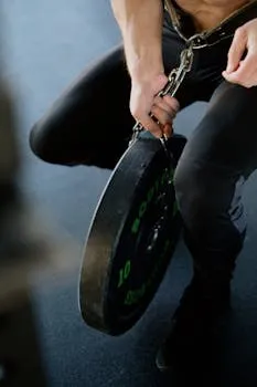 Close-up of a bodybuilder holding weighed chains in a gym setting.