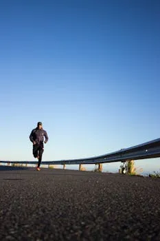 An athletic man jogging on an open road with a clear blue sky in Cape Town,