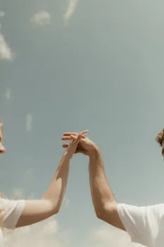 Close-up of a couple holding hands against a blue sky, symbolizing unity and