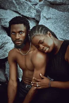 Tender outdoor portrait of a shirtless man and woman resting on rocky