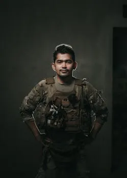 A stern-looking soldier in military uniform poses for a portrait indoors.