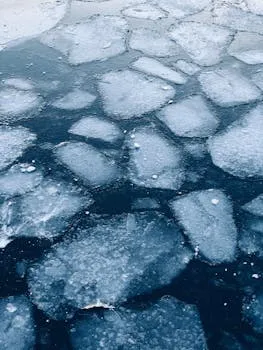 Captivating abstract pattern of frozen ice floes over dark water surface in