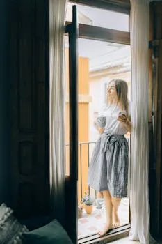 A woman stands on a balcony holding a coffee mug, enjoying the peaceful