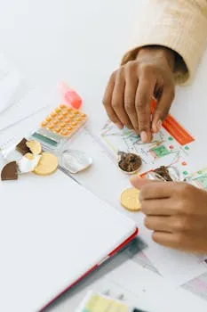 Hands arranging chocolate coins and documents, symbolizing finance and strategy.