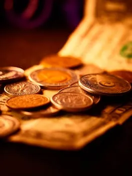 A detailed close-up of assorted currency coins and paper bills in warm