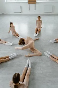 Group of children stretching in a dance studio wearing leotards and socks.