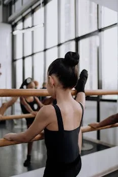 A young girl in a ballet class practices at the barre in a dance studio.