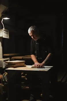 Focused male master standing at router table while working with wooden plank