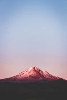 Jagged mountain peak under a violet and gold sunset sky.