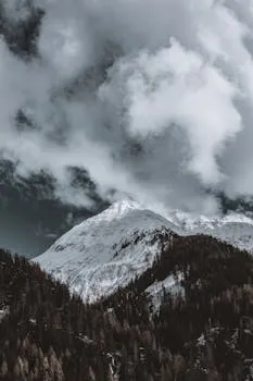 Snow-covered mountain summit under dramatic winter clouds, stark and silent.