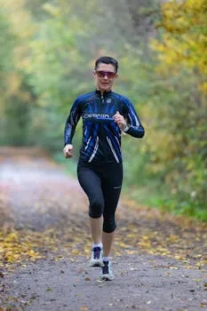 Woman in activewear jogging on a forest path in Frankfurt, capturing an