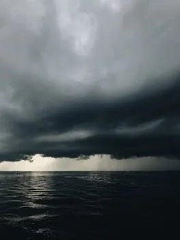 A dramatic view of storm clouds hovering over a dark ocean, creating a moody