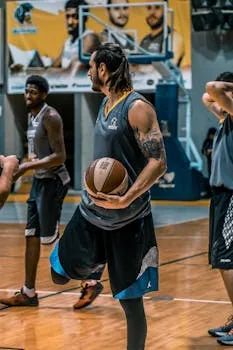 Male athletes practicing basketball on an indoor court, focusing on drills and teamwork.
