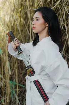 Woman in martial arts uniform holding katana sword