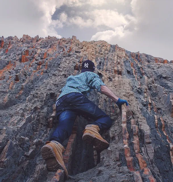 Man climbing steep rock face, embodying deliberate effort and long-term