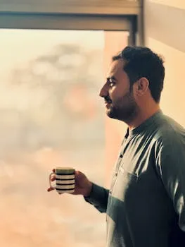 Man waking at 5 AM looking out a window in the quiet morning hours