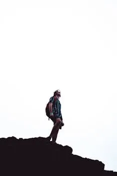 Man standing on a cliff edge with a backpack, embodying adventure and