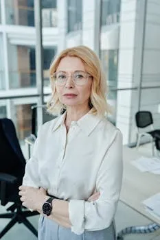 Professional woman with glasses standing confidently in a modern glass