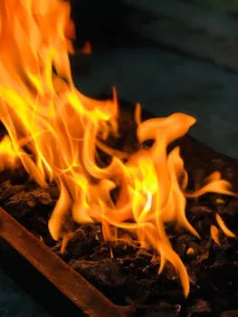 Intense orange flames burning over charcoal