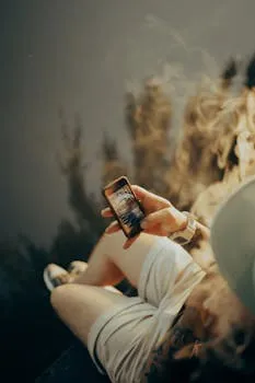 A young adult relaxing outdoors, browsing a smartphone while enjoying the