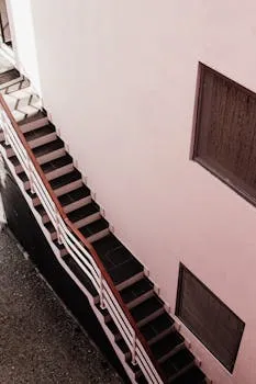A modern staircase along a concrete wall featuring metal railings, viewed
