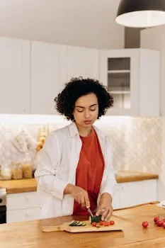 Woman slicing vegetables in a bright kitchen for a healthy meal preparation.