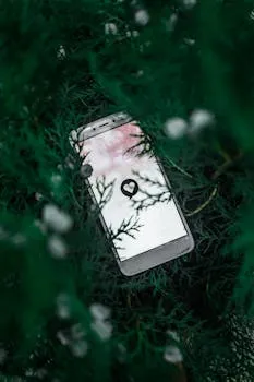 Mobile phone displaying a heart icon nestled among green foliage, creating a