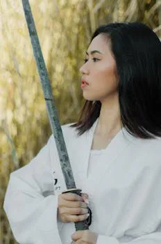 Portrait of a young woman holding a sword, practicing martial arts outdoors
