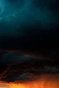 Dramatic storm clouds with vibrant hues of blue and orange at sunset.