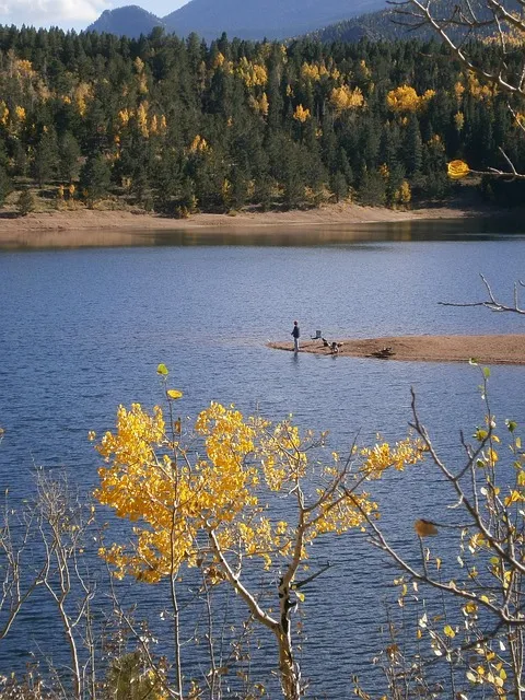 Solitary person fishing at a calm mountain lake reflecting minimalist