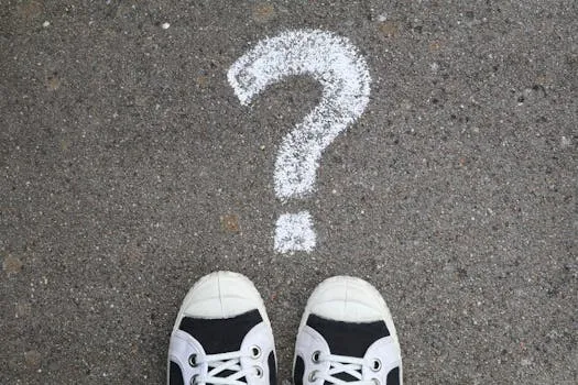 Sneakers on pavement with a chalk question mark, symbolizing curiosity or