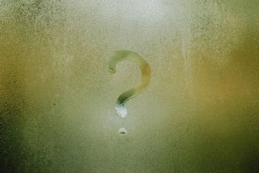 Translucent wet glass window covered with water drops with question mark on
