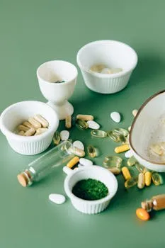 Assorted natural supplements and pills in ceramic bowls on a green