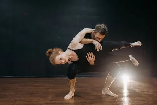 Two dancers performing a contemporary dance routine indoors, showcasing