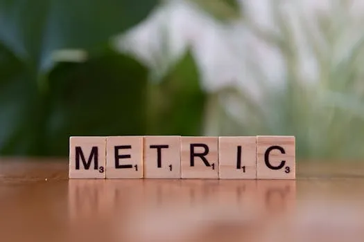 Close-up of wooden tiles spelling Metric on a table, with a blurred green