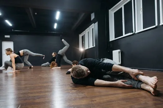 Group of dancers practicing in a modern dance studio, showcasing flexibility